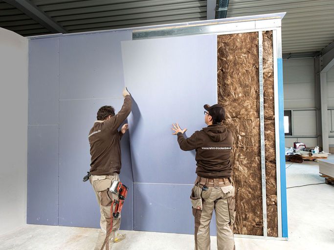Instaladores montando placas de alta densidad en tabique acústico de construcción en seco